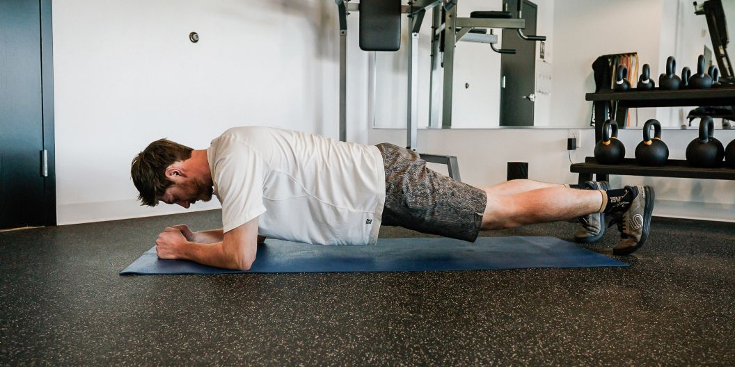 Gym goer performs standard plank. 